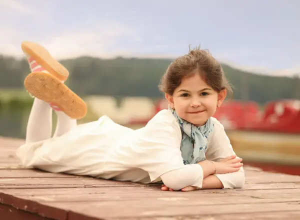 Smiling girl lying on a wooden dock, outdoor photography by Photoholic, Rockland County NY
